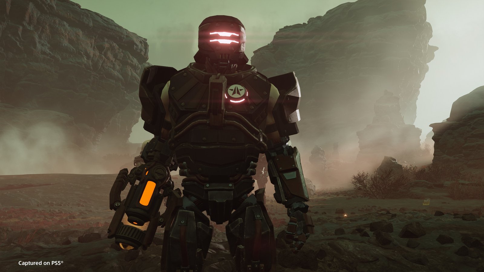 A heavily armored Cyborg Legion soldier with a glowing visor and an arm-mounted weapon stands in a dusty canyon