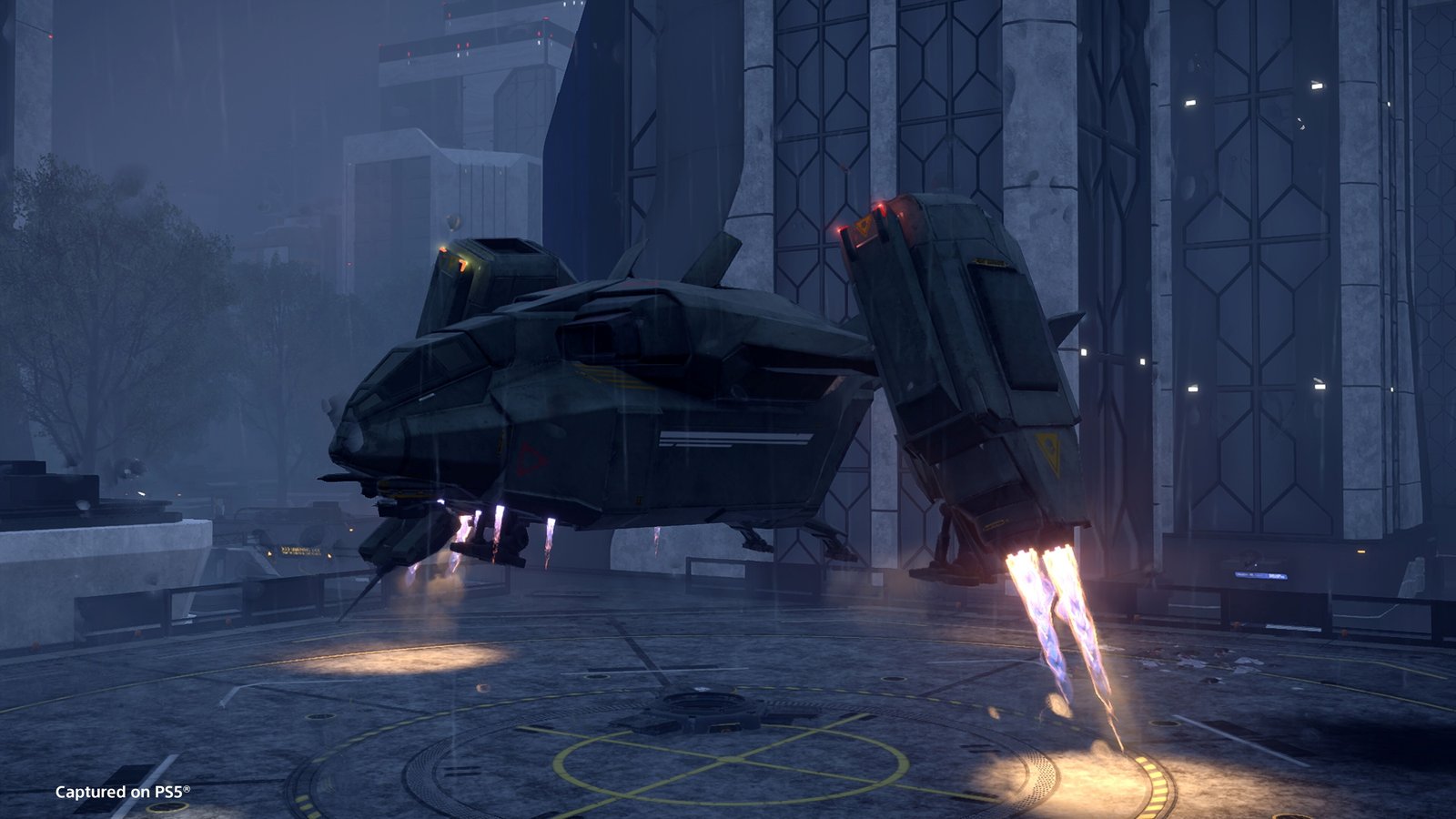 The Pelican-1 shuttle descends on its thrusters onto a marked landing pad between tall buildings in the rain at night
