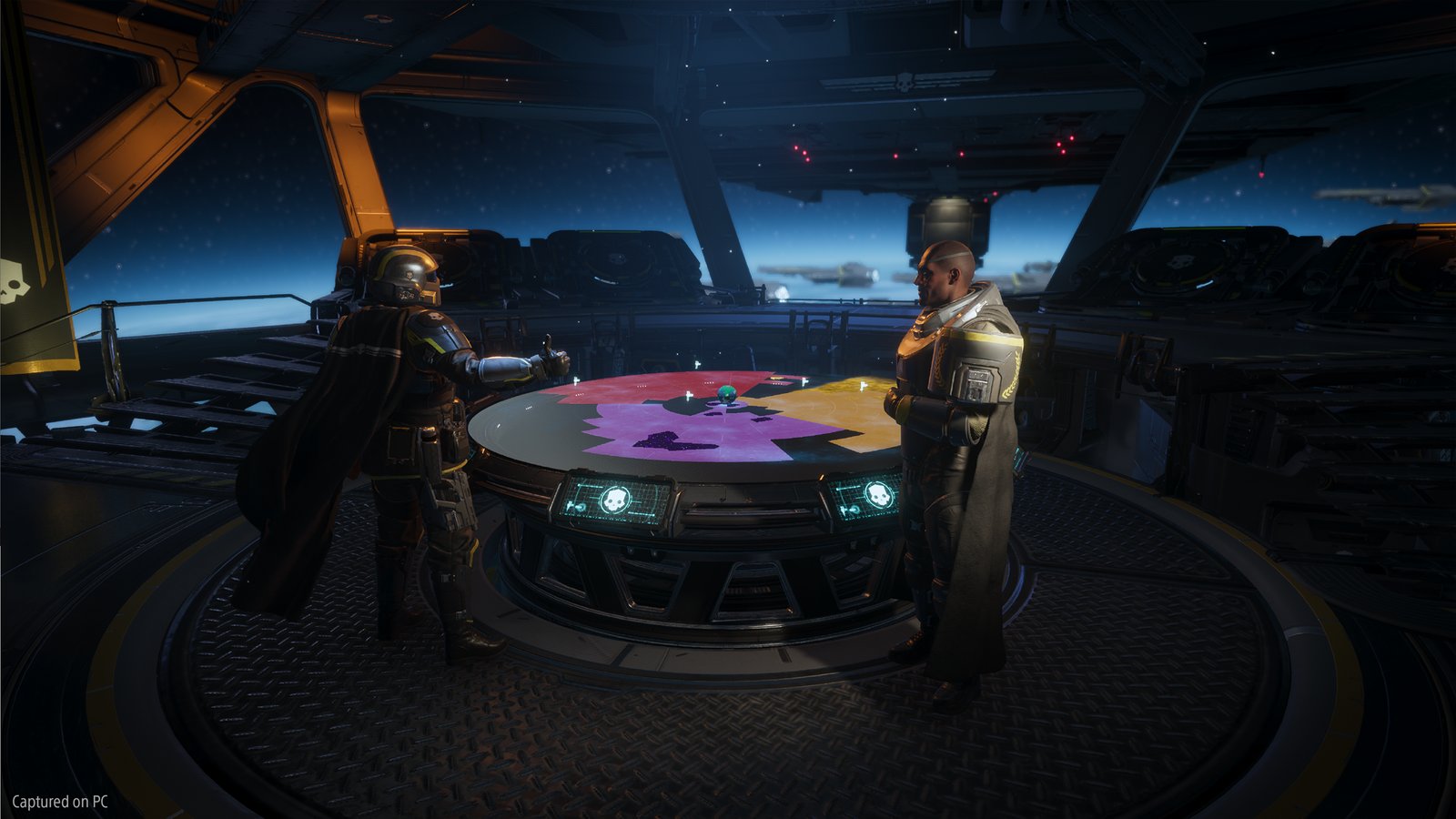 A Helldiver gives a thumbs-up to an officer across a round galaxy-map table whose territories glow red, violet and yellow