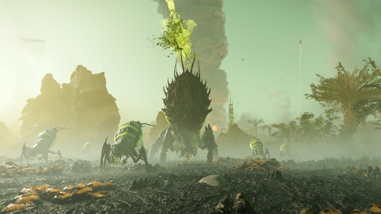 Bile Spewers with glowing green acid sacs gather in a green haze around a larger spiked Terminid that vents green bile into the air